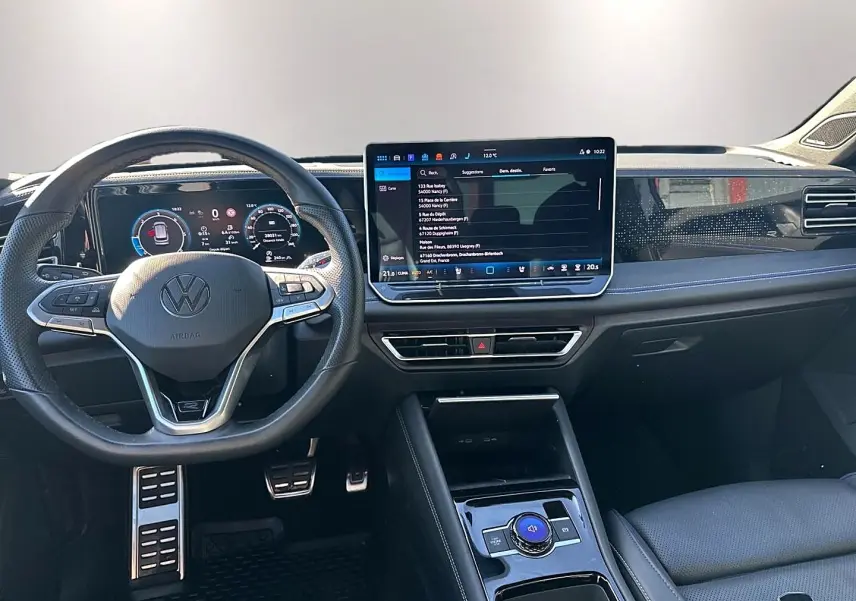 Vue intérieure avant du Volkswagen Tiguan 2024, tableau de bord noir avec écran tactile et volant multifonction cuir.