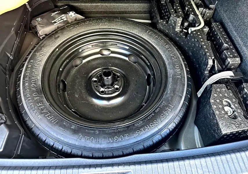Vue rapprochée de la roue de secours noire dans le coffre du Volkswagen Tiguan gris dauphin 2024.