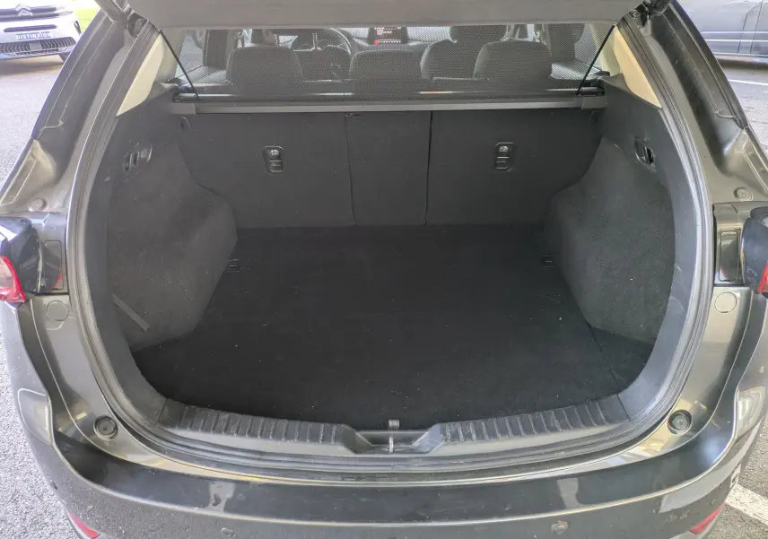 Coffre ouvert vu de l'arrière d'un Mazda CX-5 gris 2020, montrant un espace de chargement vide et propre.