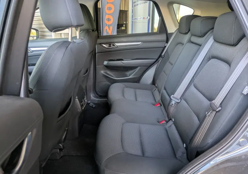 Vue intérieure arrière côté droit du Mazda CX-5 2020 gris, montrant les sièges arrière en tissu noir et les ceintures de sécurité.