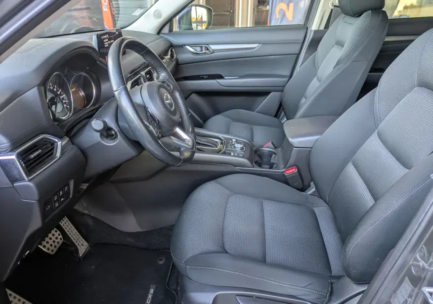 Intérieur avant droit du Mazda CX-5 gris 2020, sièges tissu noirs et console centrale avec boîte automatique visible.