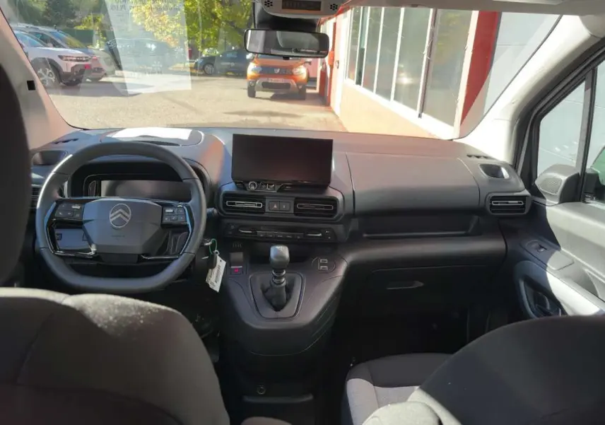 Vue intérieure avant du Citroën Berlingo blanc Kaolin 2026, tableau de bord moderne avec écran tactile et volant multifonctions.