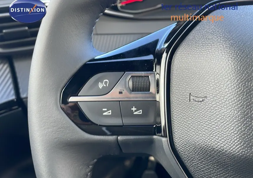 Gros plan sur les commandes gauche du volant noir du Peugeot 2008 blanc Okenite Metal 2025.