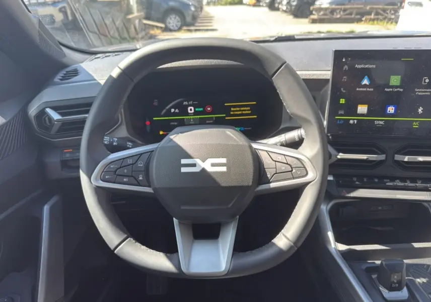 Vue intérieure centrée sur le volant cuir et le tableau de bord digital du Dacia Bigster gris schiste 2025.