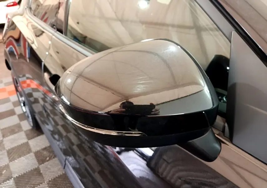 Rétroviseur côté gauche noir brillant d'un Nissan Juke Hybrid 143 Business+ 2022, vue rapprochée en intérieur.