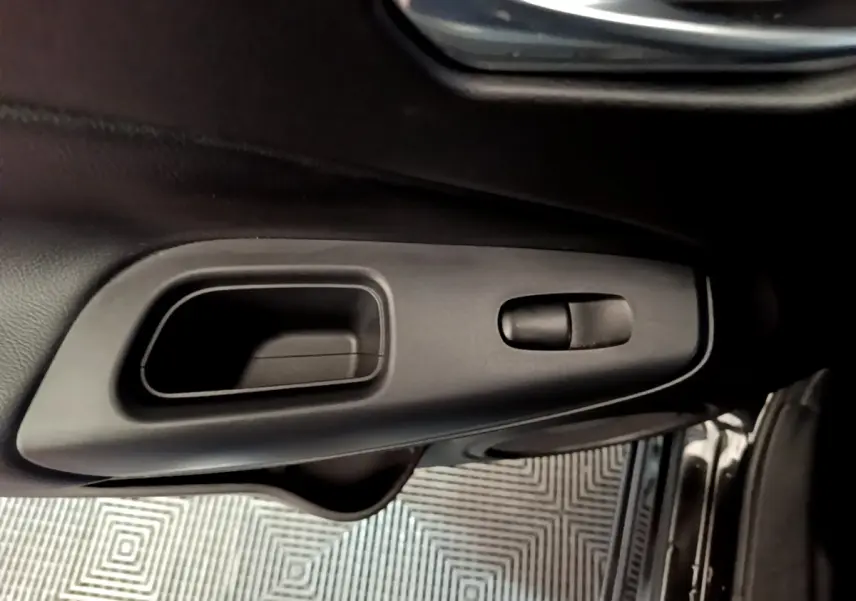 Poignée intérieure de porte côté conducteur du Nissan Juke Hybrid 2022 noire, avec commande de verrouillage intégrée.