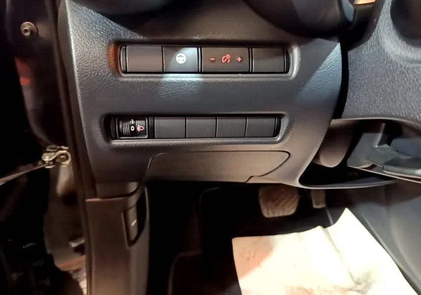 Vue intérieure côté conducteur du tableau de bord noir avec commandes d’éclairage et réglages du Nissan Juke Hybrid 2022.