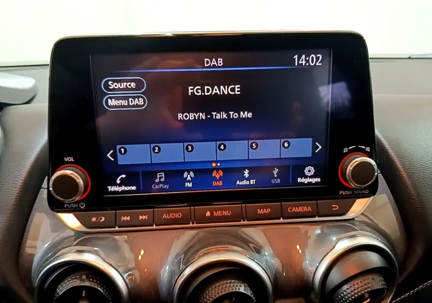 Écran tactile central 8 pouces du Nissan Juke Hybrid 2022 montrant l'interface radio DAB avec commandes audio et climatisation.