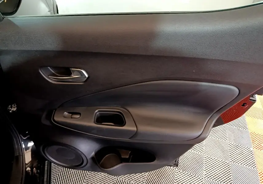 Vue intérieure côté gauche de la porte noire du Nissan Juke Hybrid 2022 avec poignée et haut-parleur intégrés.