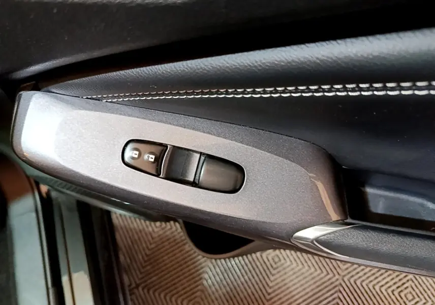 Détail de la commande de verrouillage des portes sur la porte intérieure côté conducteur du Nissan Juke Hybrid noir 2022.