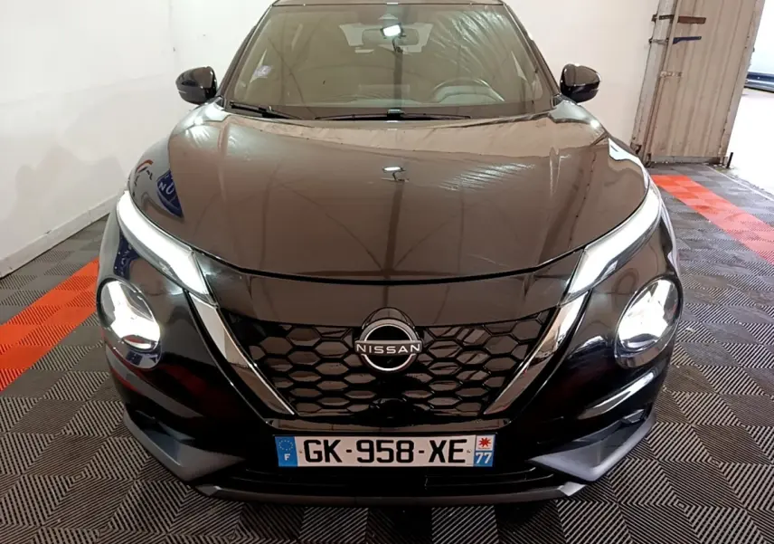 Vue avant d'un Nissan Juke Hybrid 143 Business+ noir avec calandre en nid d'abeille et phares allumés.
