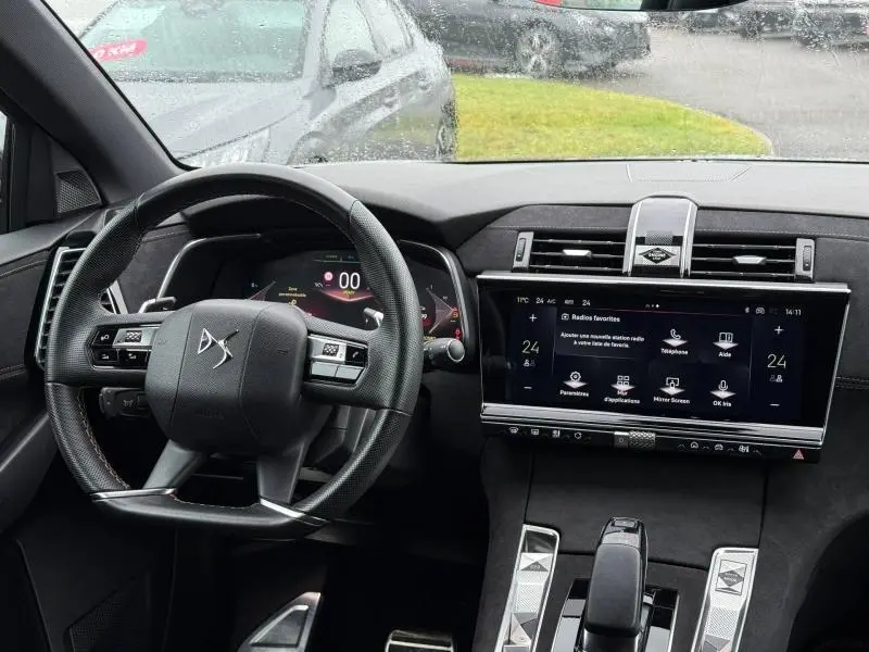 Vue intérieure du tableau de bord et volant du DS7 E-TENSE 225ch gris 2024, avec écran tactile central et commandes modernes.