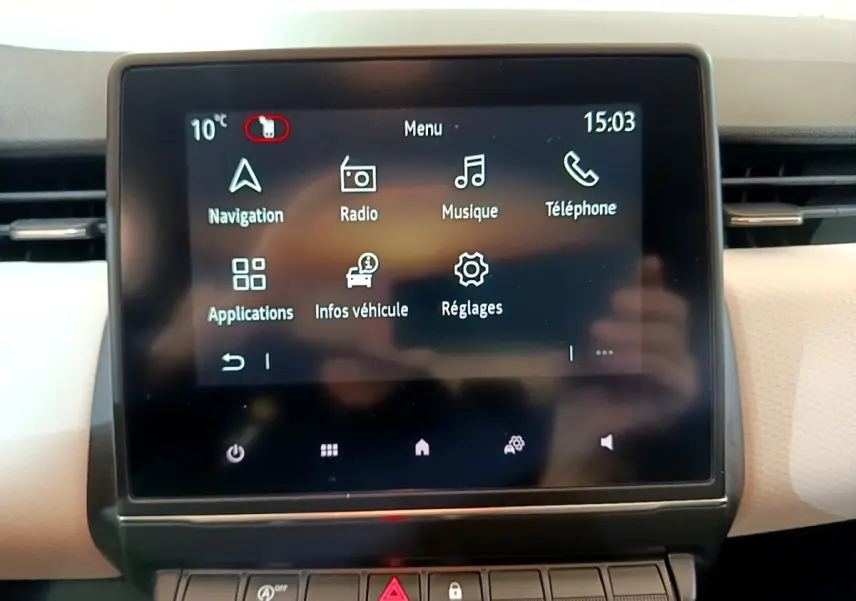 Écran tactile central de la Renault Clio bleu, affichant le menu principal avec navigation et musique.