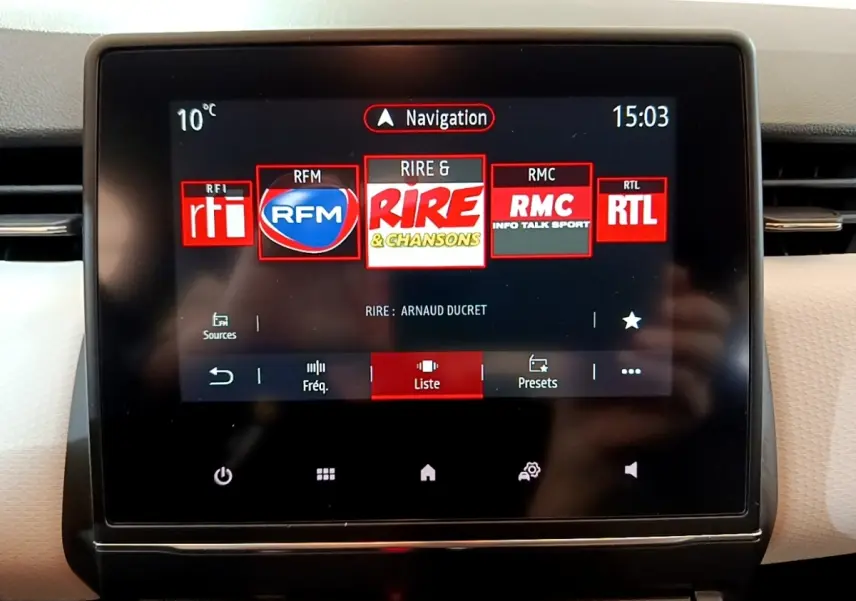 Écran tactile central de la Renault Clio bleu 2022 affichant les stations radio et la navigation.