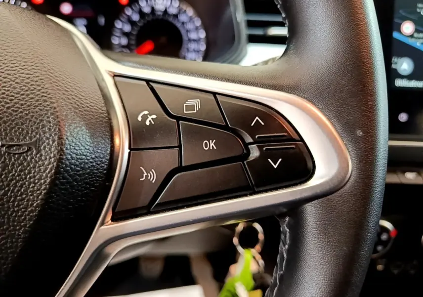 Gros plan sur le côté droit du volant cuir synthétique de la Renault Clio bleu, avec commandes multifonctions visibles.