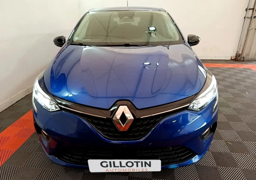 Vue frontale d'une Renault Clio Evolution bleu électrique avec phares LED allumés dans un garage.