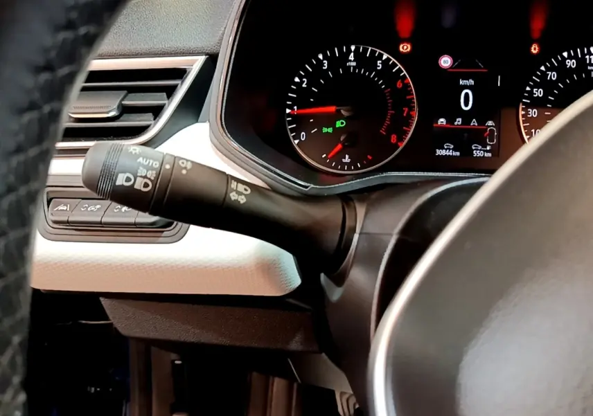 Vue rapprochée du tableau de bord et du commodo d’éclairage d’une Renault Clio bleu, affichage digital au centre.