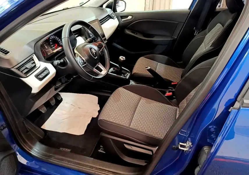Vue intérieure côté conducteur d’une Renault Clio bleu 2022, volant cuir multifonctions et sièges tissu gris à motifs.