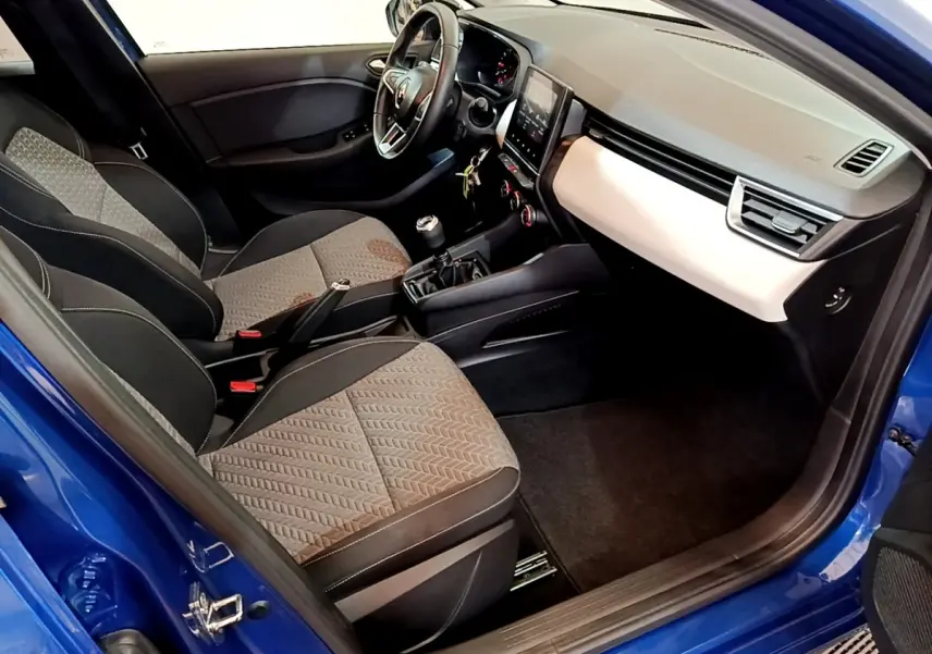 Vue intérieure côté passager de la Renault Clio Evolution bleu 2022, montrant sièges tissu et tableau de bord moderne.