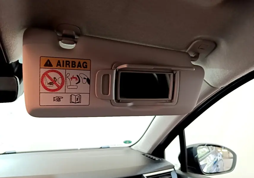 Intérieur de la Renault Clio Evolution bleu, vue côté passager sur pare-soleil avec miroir et avertissement airbag.