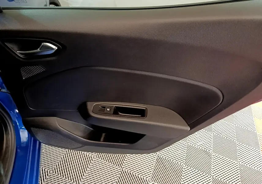 Vue intérieure de la porte avant gauche d’une Renault Clio bleu 2022, avec poignée et commande de vitre noire.