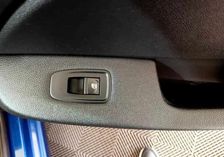 Gros plan sur le bouton de commande de la vitre électrique côté conducteur d'une Renault Clio bleu 2022.