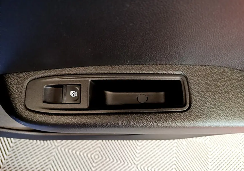 Gros plan sur le bouton de commande de lève-vitre côté conducteur de la Renault Clio bleu 2022.