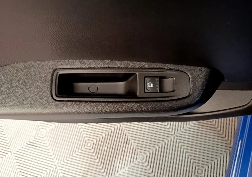 Gros plan sur la commande de lève-vitre côté conducteur de la porte intérieure d'une Renault Clio bleu 2022.