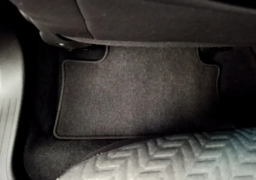 Vue rapprochée du tapis de sol noir côté passager avant de la Renault Clio Evolution bleu 2022.