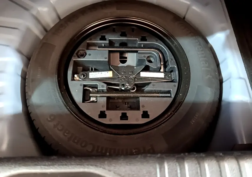 Gros plan sur la roue de secours et les outils de bord dans le coffre d'une Renault Clio bleu 2022.