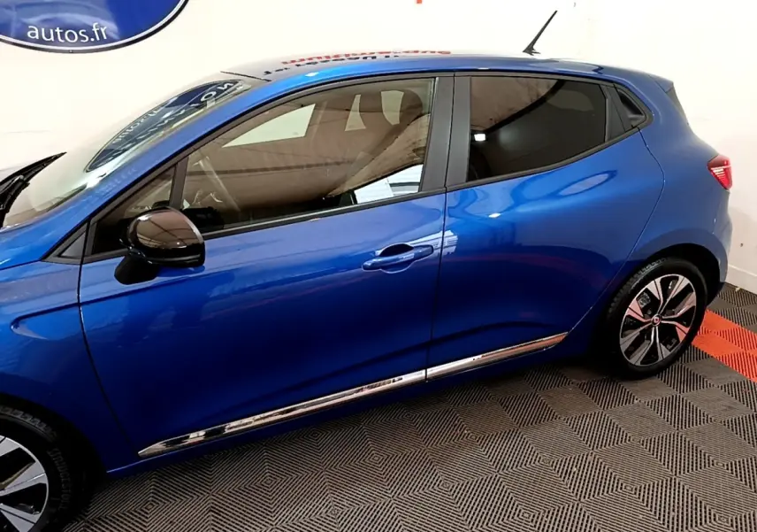 Profil droit d'une Renault Clio Evolution bleu 2022 avec rétroviseurs noirs et jantes stylisées en intérieur showroom.