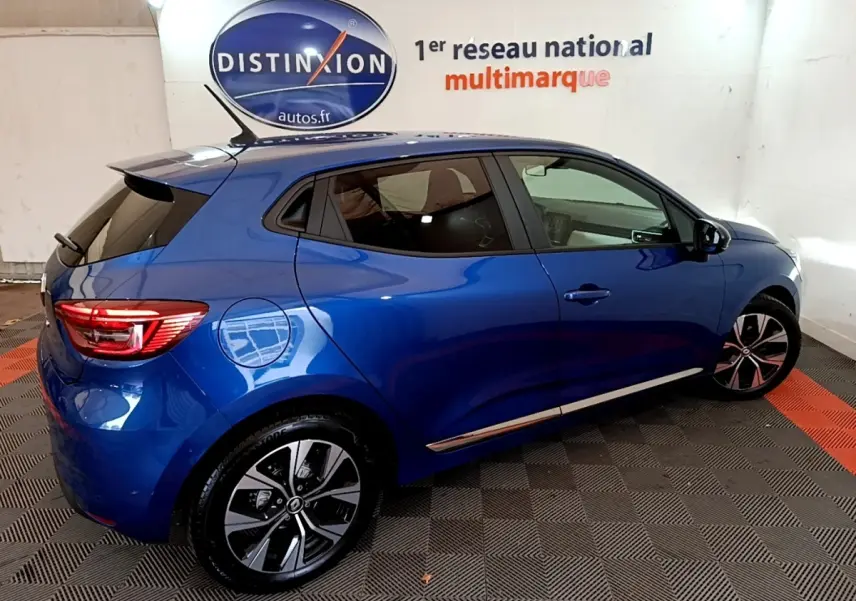 Vue côté droit arrière d'une Renault Clio Evolution bleu 2022 avec jantes alliage et toit spoiler noir.