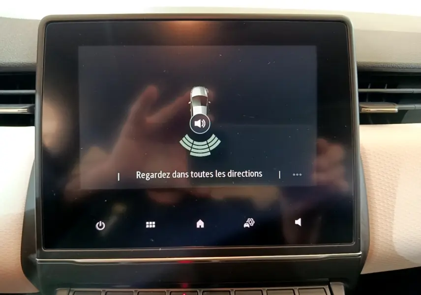 Écran tactile central de la Renault Clio Evolution bleu 2022 affichant l'aide au stationnement avec message de vigilance.