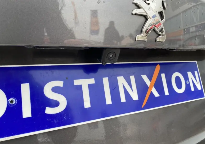 Gros plan arrière sur la caméra de recul et le logo Peugeot d'une 2008 gris foncé avec plaque Distinxion.