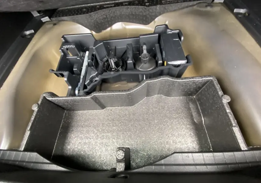 Coffre ouvert d’une Peugeot 2008 gris foncé, montrant le rangement sous plancher avec outils de bord.