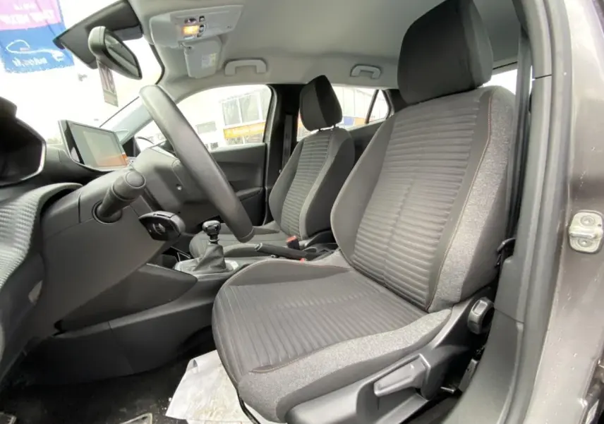 Vue intérieure côté conducteur de la Peugeot 2008 gris foncé, montrant les sièges avant et le volant avec boîte manuelle.