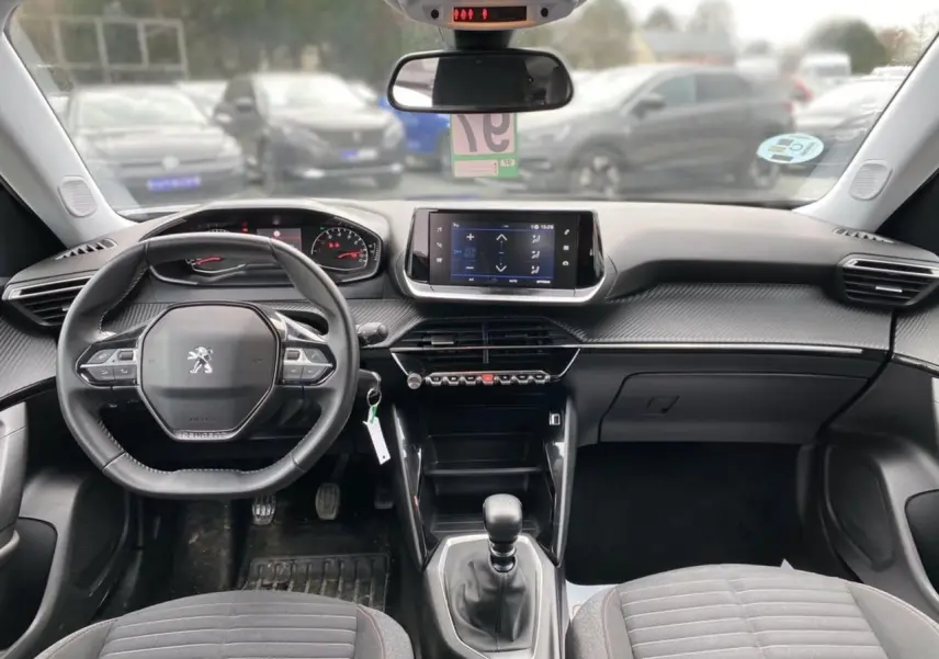 Vue intérieure avant du Peugeot 2008 2021, tableau de bord noir avec écran tactile et volant compact multifonctions.