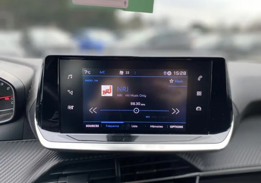 Écran tactile central du Peugeot 2008 2021 affichant la radio NRJ avec commandes tactiles et design moderne.