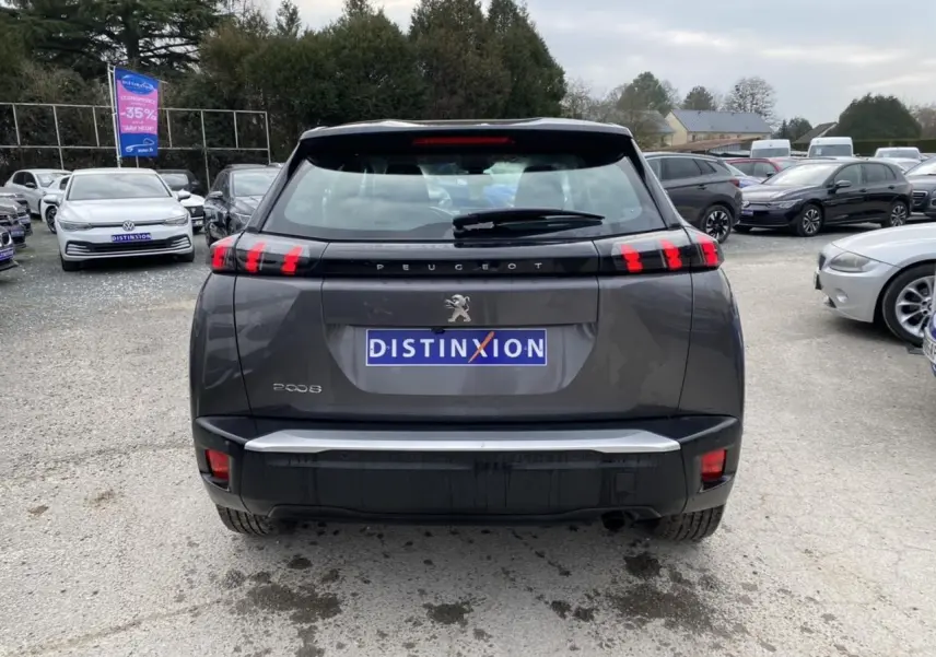 Vue arrière d'un Peugeot 2008 gris foncé avec feux arrière à LED en forme de griffes, sur un parking extérieur.