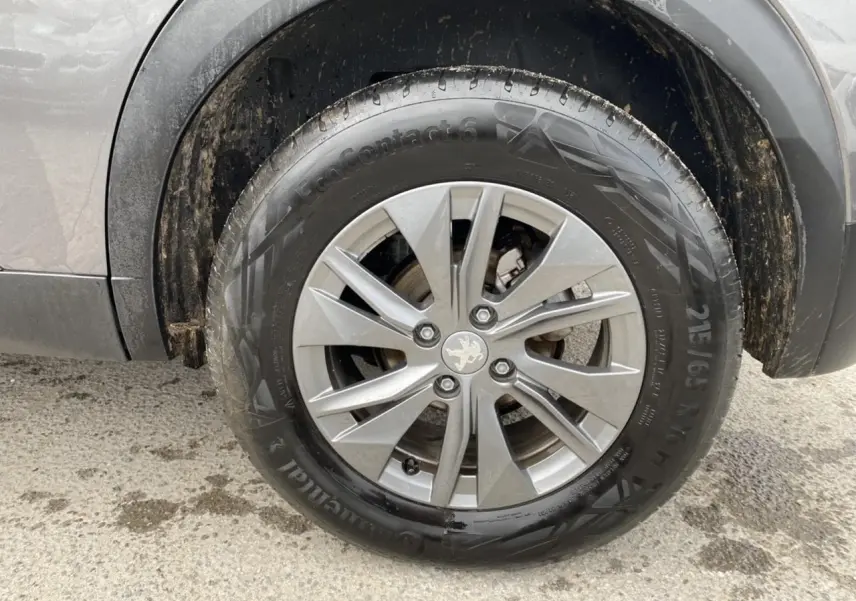 Gros plan sur la roue avant droite du Peugeot 2008 gris foncé, jante alliage avec logo lion au centre.