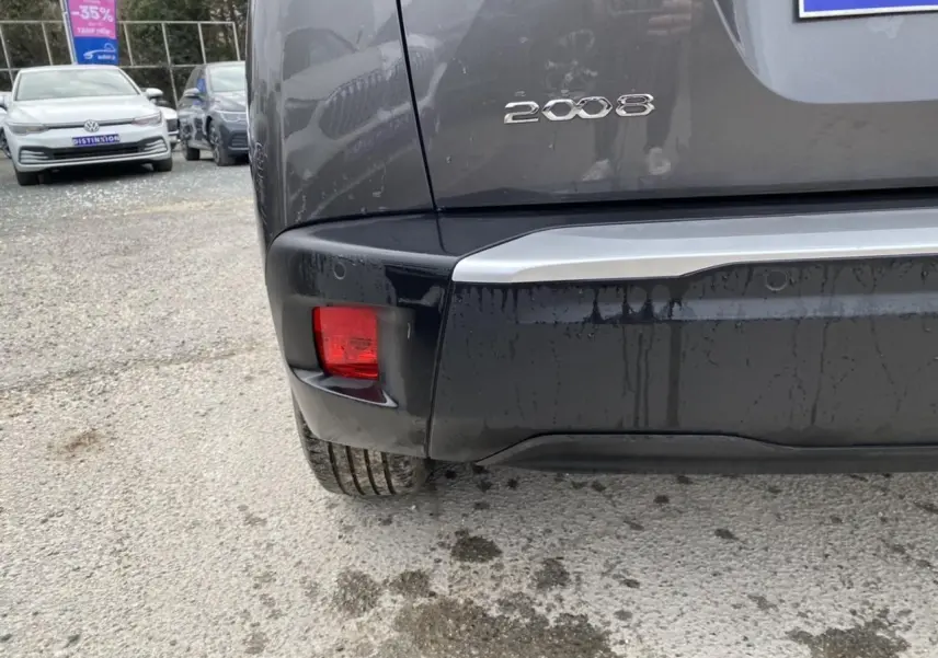 Vue rapprochée du coin arrière gauche d’un Peugeot 2008 gris foncé avec feux arrière et logo visibles.