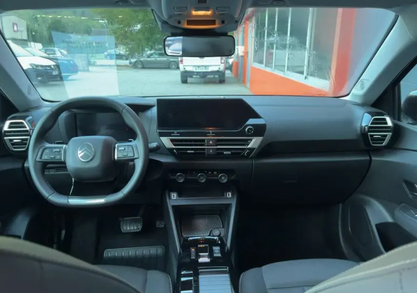 Vue intérieure avant centrée sur le tableau de bord et le volant cuir multifonctions de la Citroën C4 hybride 2025.