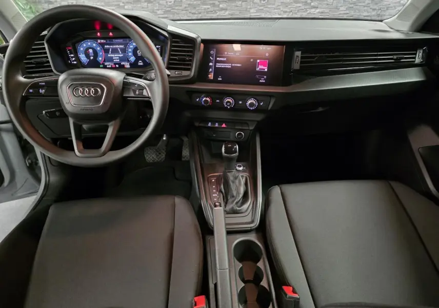 Intérieur de l'Audi A1 Sportback 2020 vu de face, tableau de bord noir avec volant multifonction et écran tactile central.