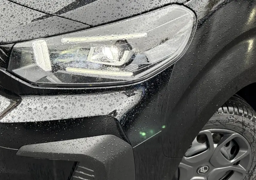 Gros plan sur l'avant droit noir Perla du Citroën Jumpy 2025 avec phare Full LED et gouttes de pluie visibles.