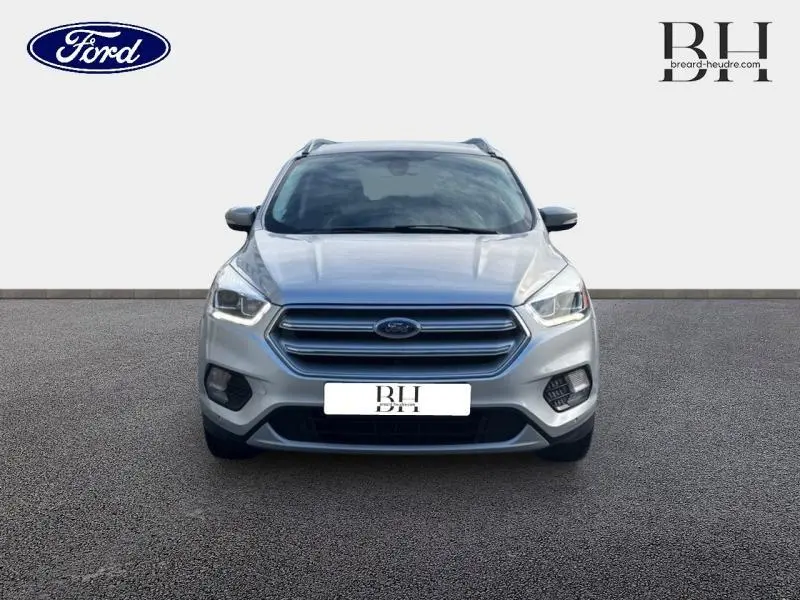 Vue frontale d'un Ford Kuga gris lunaire 2017 avec calandre hexagonale et phares LED allumés.