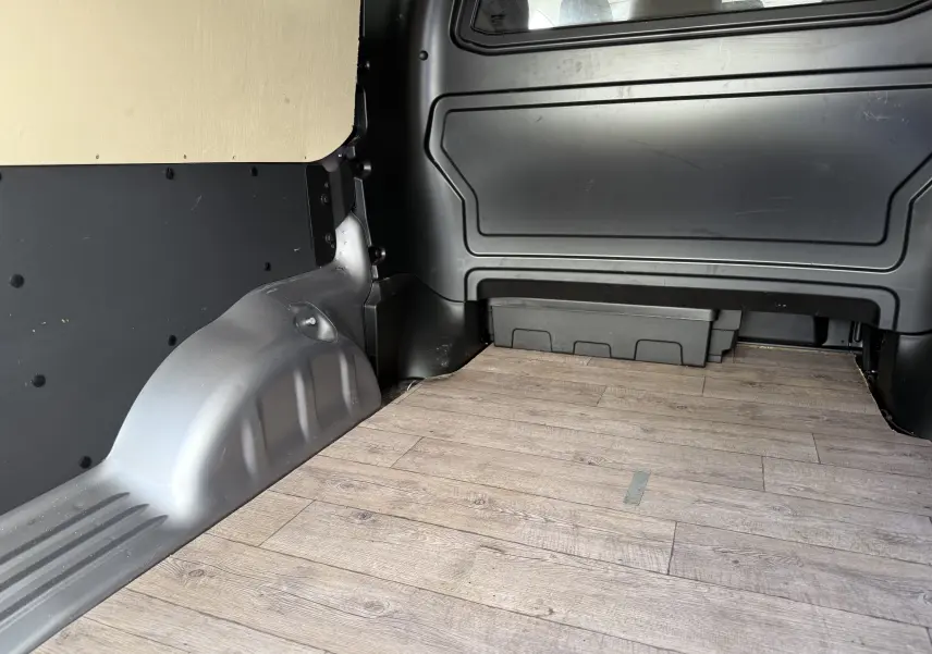 Vue intérieure arrière du coffre gris du FIAT Scudo Cabine Approfondie 2022 avec plancher en bois et cloison noire.
