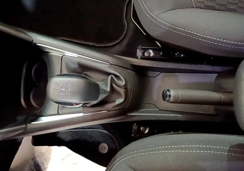 Vue plongeante sur la console centrale noire de la Peugeot 208 blanche, avec levier de vitesse manuel et frein à main.