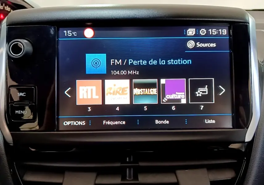 Écran tactile central de la Peugeot 208 blanc, affichant les stations radio FM avec interface moderne.