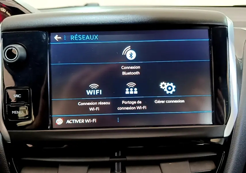 Écran tactile central du tableau de bord de la Peugeot 208 blanc, affichant les options de connexion Bluetooth et Wi-Fi.