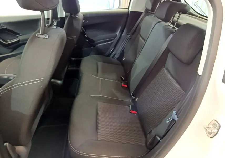 Vue intérieure côté droit des sièges arrière noirs de la Peugeot 208 blanche, montrant les ceintures et appuie-têtes.